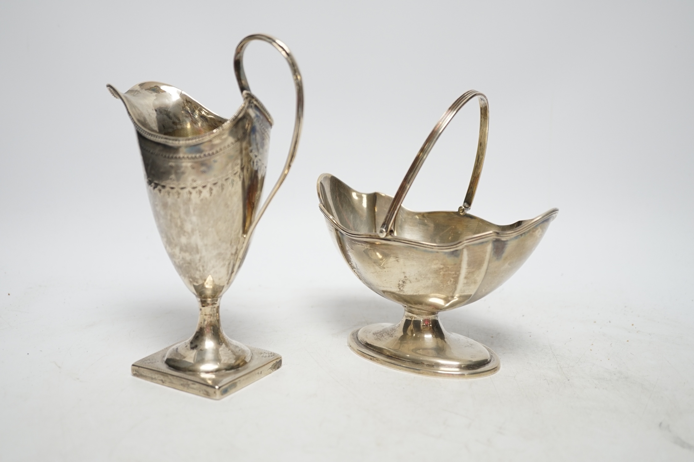 A late Victorian silver oval sugar basket, by Thomas Bradbury & Sons, London, 1894, height length 13.5cm (fair condition), together with a George III silver cream jug, marks rubbed, 8.5oz, (poor condition).